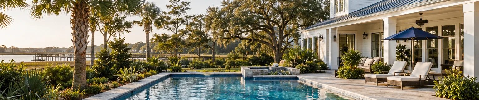 Sunlit residential swimming pool with clear blue water, edged by palmetto planting.