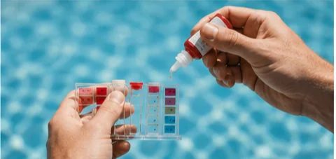 Pool water sample held against a chemical test comparator at the pool edge.